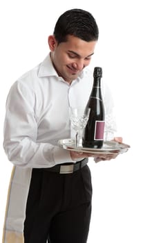 A smiling waiter, bartender, servant or attendant carrying a wine bottle and glasses.  White background.