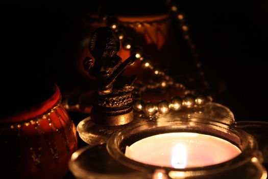 A lamp lit in front of an antique Goddess Saraswati Idol in a temple altar.