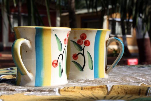 A pair of colorful coffee mugs with floral design, served on a table.