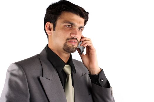 A young Indian businessman talking on his cellphone, on white studio background.