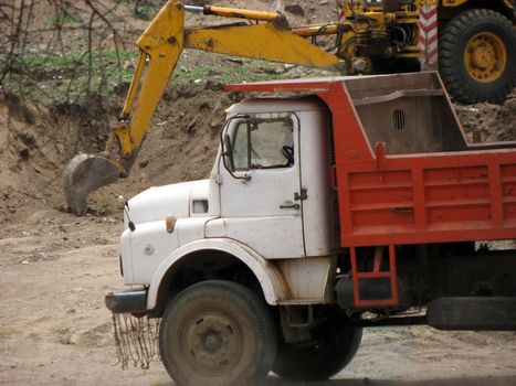 An abstract view of an old truck near a crane working at an Indian construction site.
