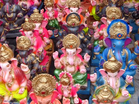 A background of colorful idols of Hindu lord Ganesha prepared for a traditional festival.