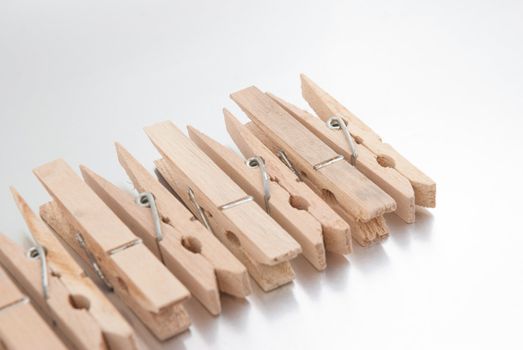Wooden clothes pegs on silver reflective background.