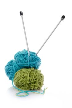 Balls of green and blue  knitting wool or yarn, with silver knitting needles.