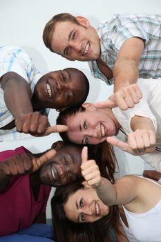 young, happy people of different backgrounds have fun and show their thumb in the direction of camera