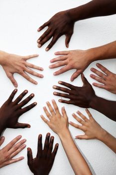 Many hands of persons of various nationalities in a circle on a white background