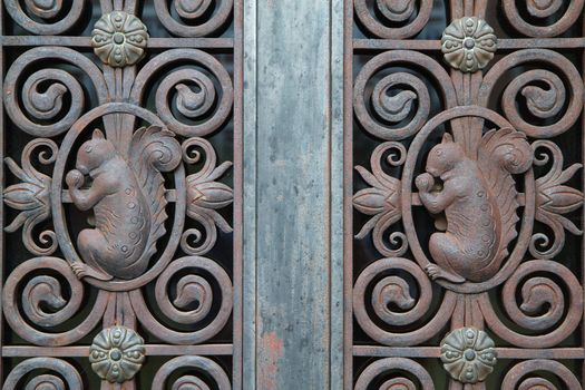 Close up portion of a wrought iron door with squirrels