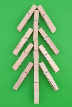 Pine tree made of wooden clothes pegs on a green background.