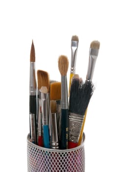 Paintbrushes in a metal mesh holder on white background.