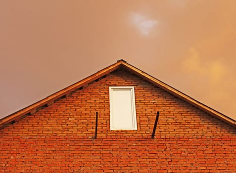 Fragment of brick house in the background reddish thunderclouds. Sitting sun illuminated the clouds