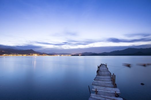 a romantic blue sunset with a jetty over a lake with an evening glow 