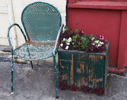 Blue green Old chair and flower box against burgandy and yellow walls