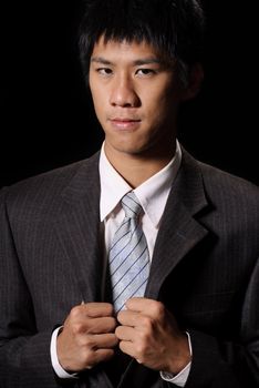 Young businessman with confident expression in dark background.
