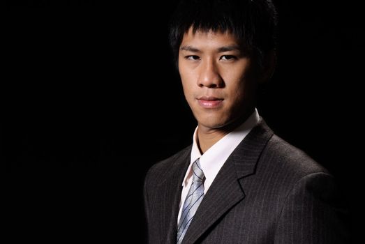 Oriental businessman, closeup portrait of Asian office man in dark background.