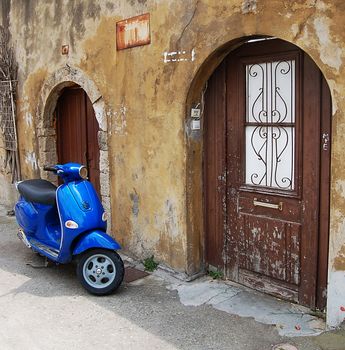 Blue scooter parked near old wall