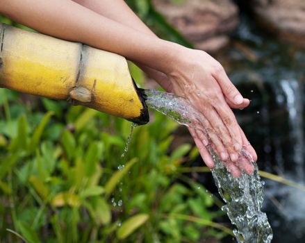 Asian woman cleaning her hands in a pure water stream
