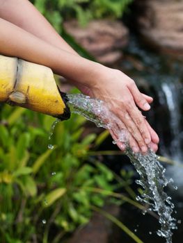 Asian woman cleaning her hands in a pure water stream