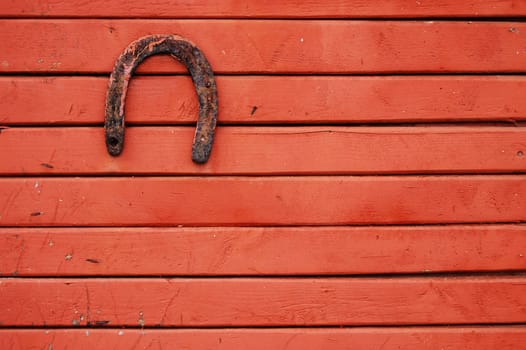 Old lucky horseshoe on red wooden wall