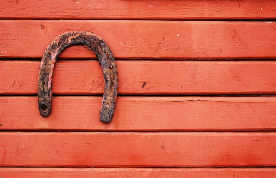 Old lucky horseshoe on red wooden wall