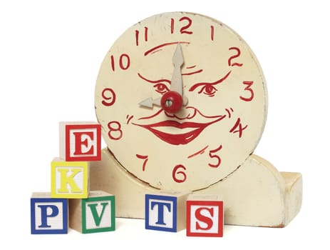 An old handcrafted wood toy clock with alphabet blocks isolated on white with clipping path. Clock is hand painted white with red numerals and a face at the center.