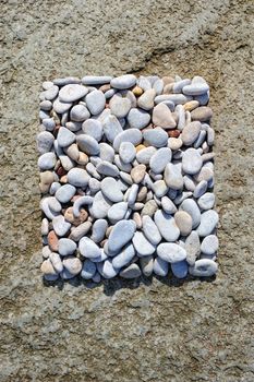 Variety of smooth pebbles on the surface of boulder