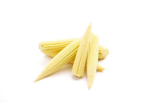 Fresh Baby Corn, isolated on a white background table, lit with a large light source from the above right.