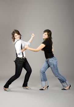 Two young beautiful sisters having fun simulating a fight  - This models are true twins
