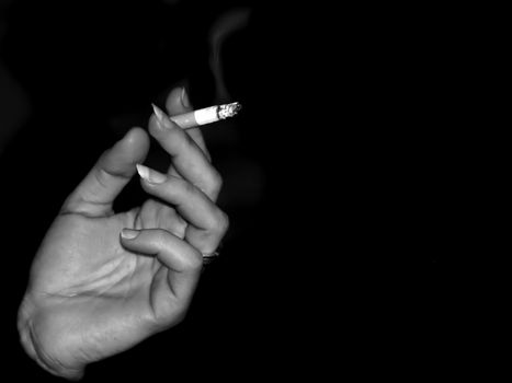 Female hand holding a burning cigarette in fingers