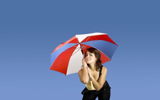 Portrait of a young happy woman posing with an umbrella on a blue background