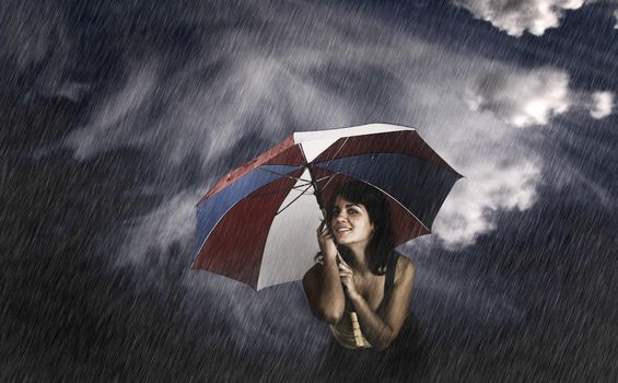 Portrait of a young happy woman posing with a umbrella under rain