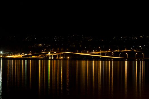 night photo of a bridge lights water reflections