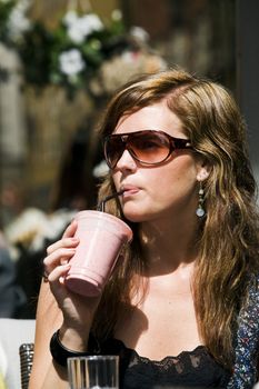 Young woman at cafe. Drinking milkshake