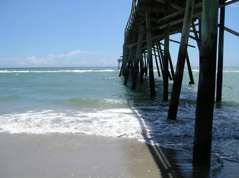 Old wooden pier and boardwalk in the middle of the beach.