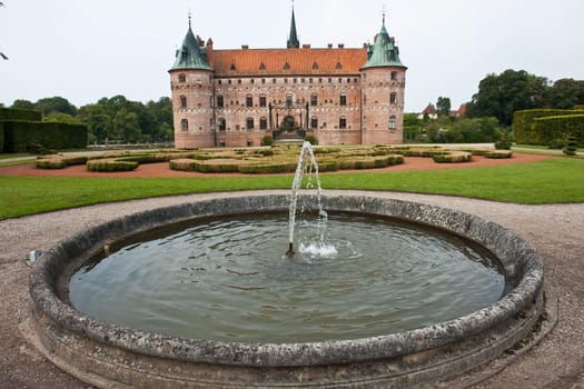 Egeskov castle slot landmark fairy tale castle in Funen Denmark view from the garden fountain