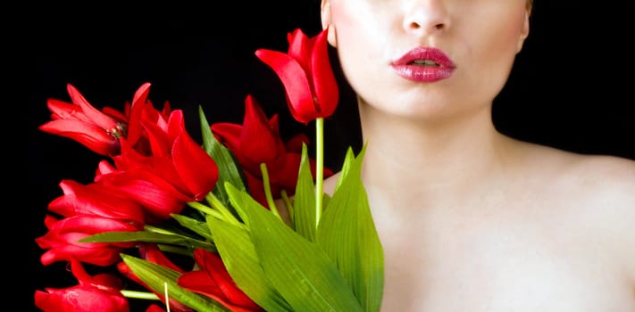 Young beautiful woman with red tulips on black background. 