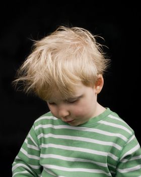 Very sad litlle boy on black background. Boy have blond hair and a bit of dirt on face
