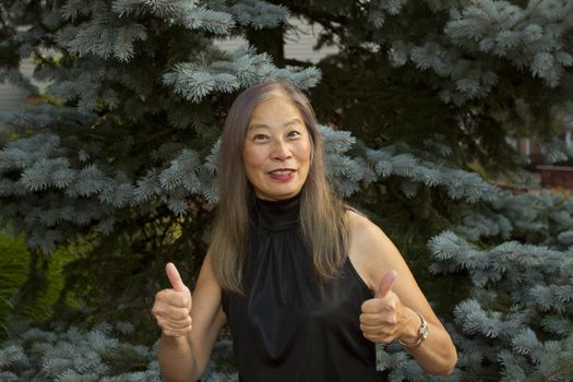 Senior Asian woman gives the thumbs up sign of success and approval