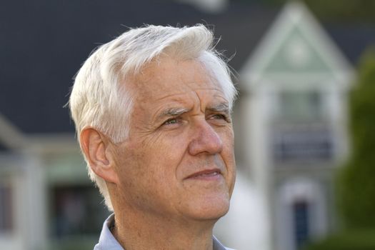 Portrait shot of senior man with defocused home outlines behind him reflect the universal effect of the recession's housing conditions
