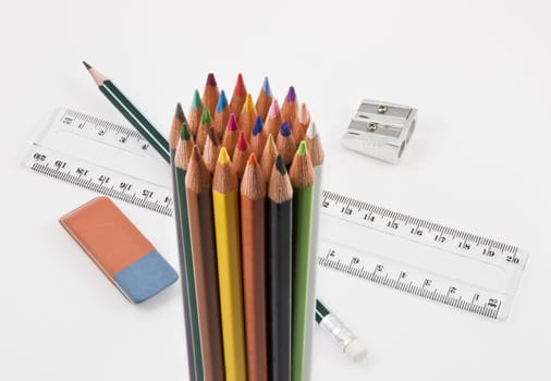 Group of colored pencils with basic school supplies on a white background