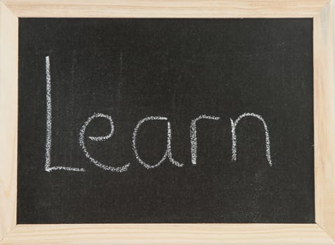 Black chalk board with wooden framed surround with the word Learn.