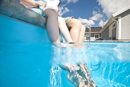 Mother and daughter with their feet in the swimming pool