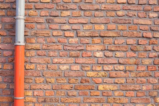 Exterior wall made of red bricks with rain gutter pipe.
