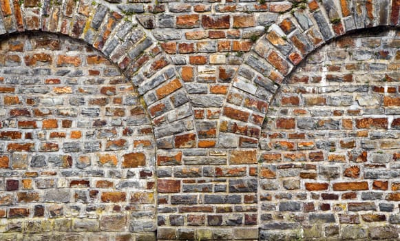 Old bricks stonewall from cut out rocks with arched brickwork