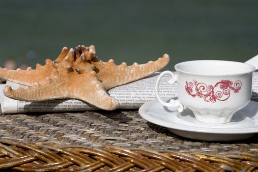 coffee cup, newspaper and starfish on wooden table