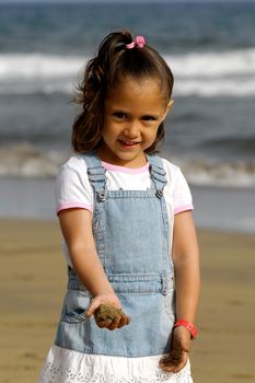 A sweet happy child on a beach playing with sand.