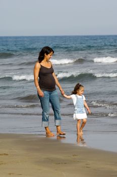 Pregnant woman walking with her child on the beach