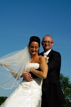 The groom is holding his arms around his bride.