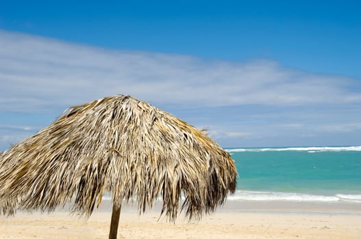 Parasol made out of palm leafs on beach.