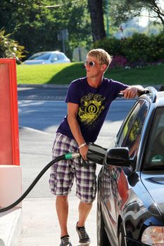 young blonde boy with sunglasses is getting fuel