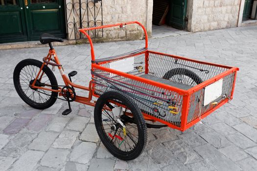 A Three wheel orange delivery bike with large carry area